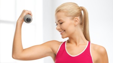 fitness and home concept - young sporty woman with light dumbbell