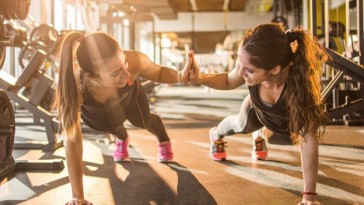 Sporty women giving high five to each other while working out together at gym.